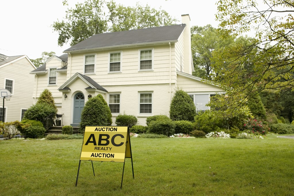 buying a home in foreclosure at auction is risky for sale sign on yard of white house