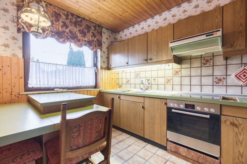home maintenance myths that cost money HDR shot of an outdated kitchen with wood paneling and avocado-green counters old appliances and light fixtures