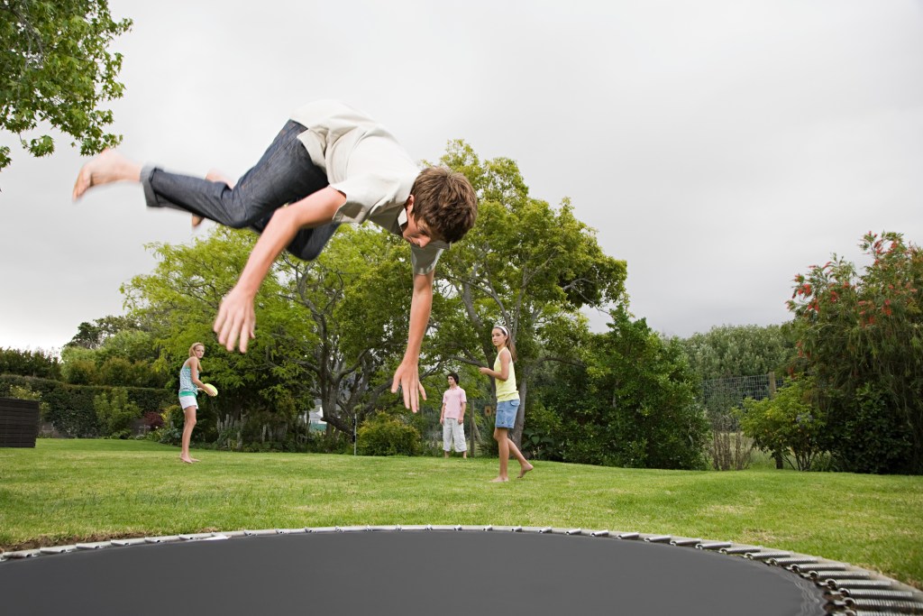 umbrella insurance coverage questions answered teenage boy doing a somersault on a trampoline in a backyard