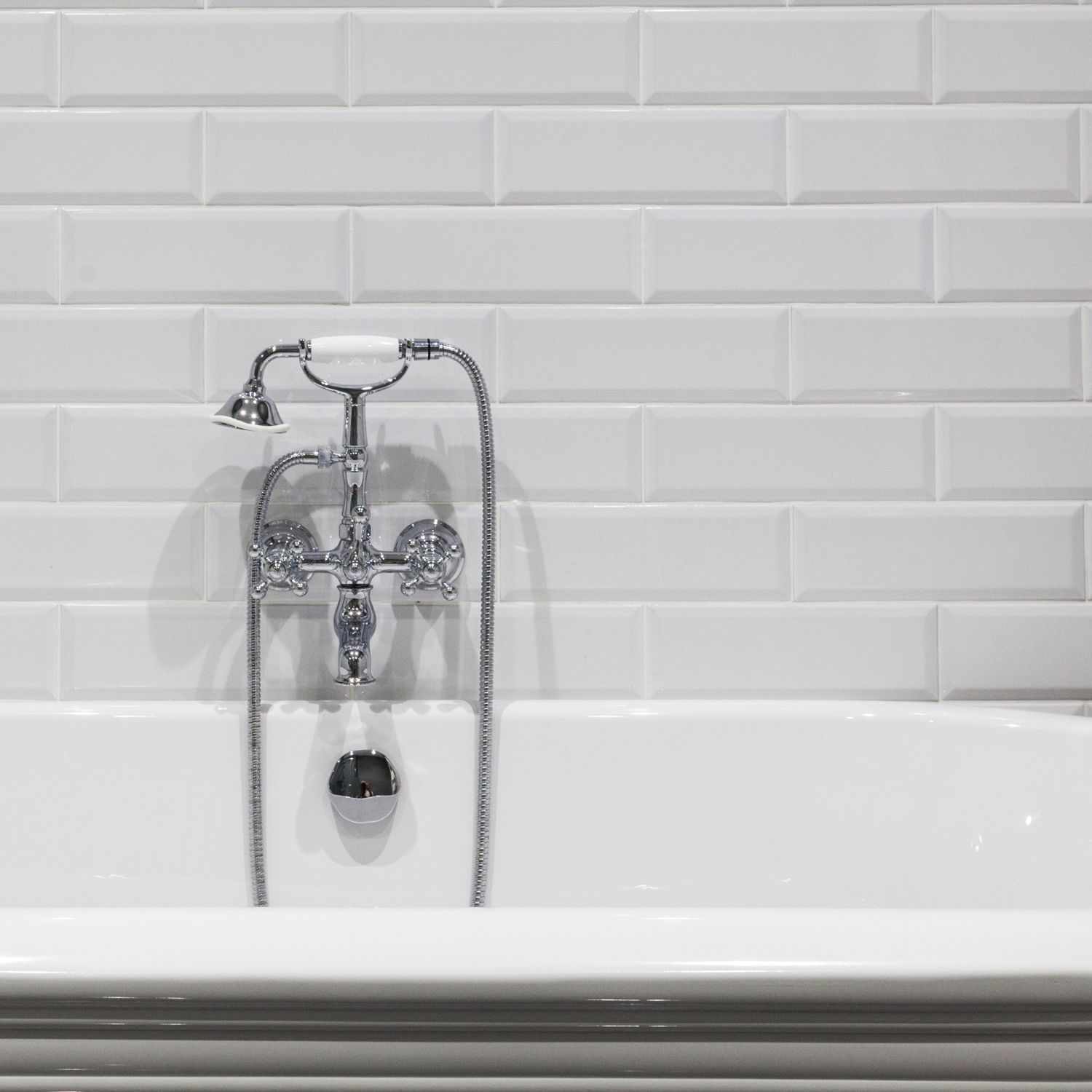 bathroom tile trends image of classic white subway tile in a bathroom with a white freestanding tub and a chrome faucet and handheld showerhead