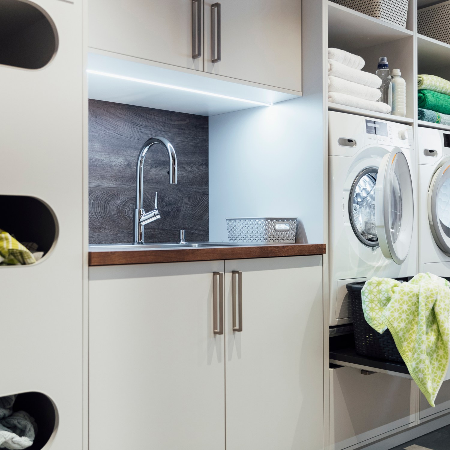 functional organized laundry room image of a modern utility area with a washing machine and dryer with lots of storage as well as a sink all integrated into the design