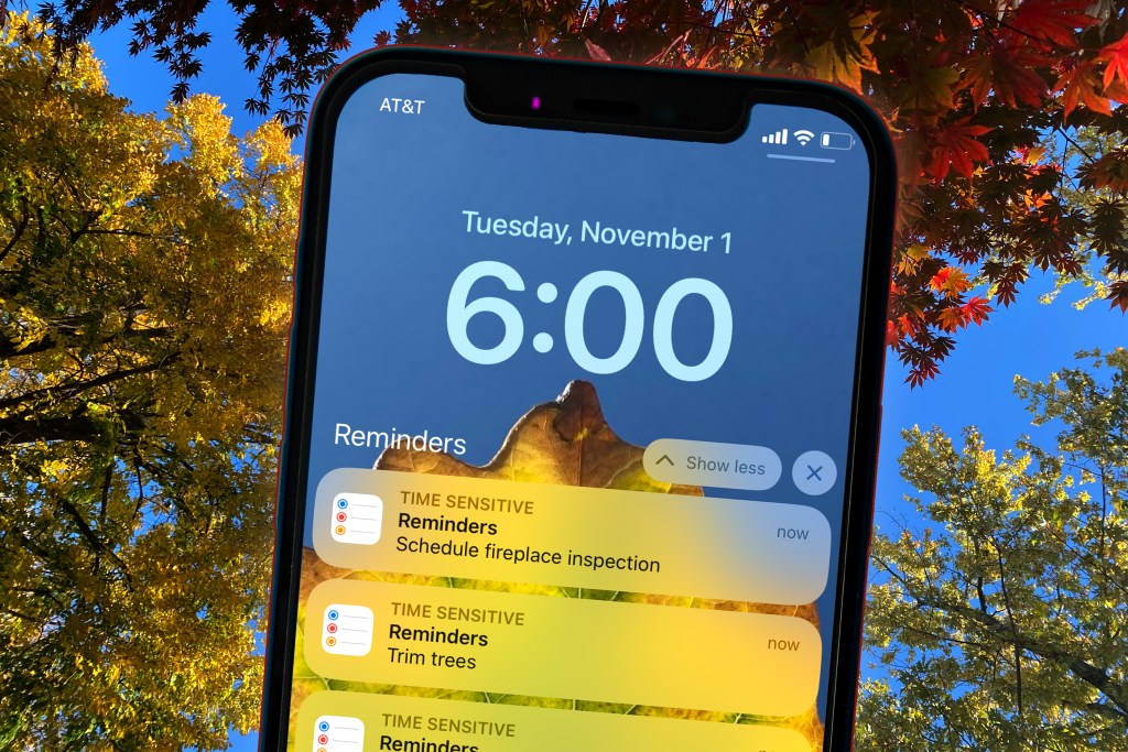 Variety of tress with colorful changing leaves of bright yellow orange red and gold in the background with a cellphone in the foreground with a list of tasks to prep for winter in November