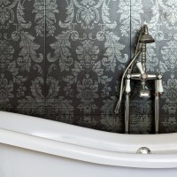 white clawfoot tub with a vintage looking brushed silver faucet and handheld shower head in front of a fancy floral dark and light gray wallpaper