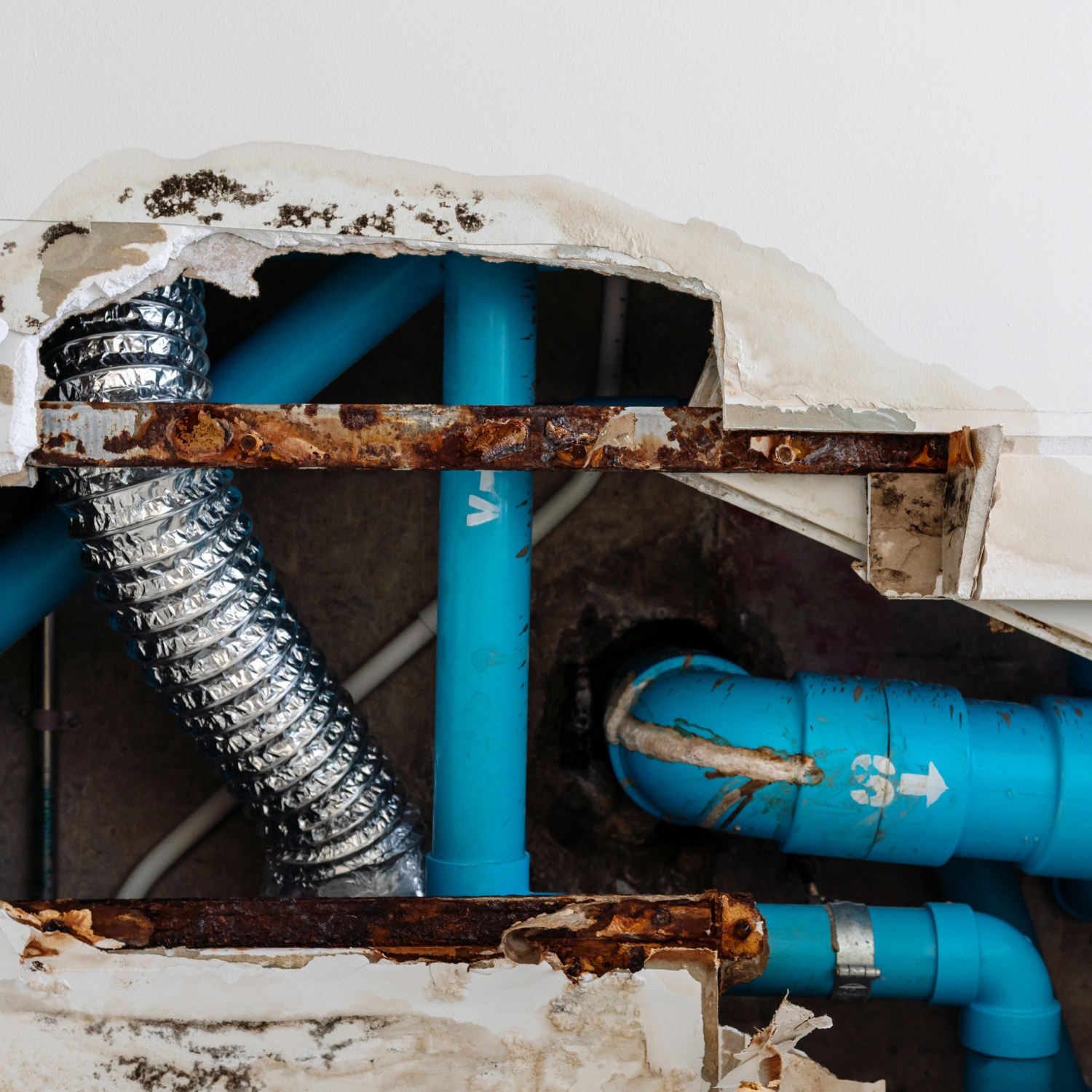 damage ceiling in restroom from a water leak out from waste piping system large hold exposed blue water and waste pipes and hvac ductwork