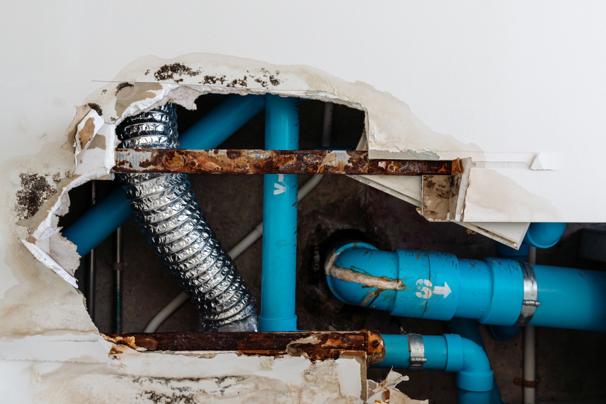 damage ceiling in restroom from a water leak out from waste piping system large hold exposed blue water and waste pipes and hvac ductwork