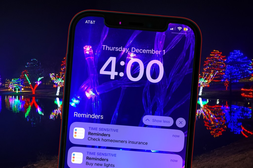 cellphone with december reminder tasks to do at home clean check insurance with background holiday lights