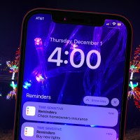 cellphone with december reminder tasks to do at home clean check insurance with background holiday lights