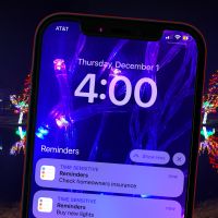 cellphone with december reminder tasks to do at home clean check insurance with background holiday lights