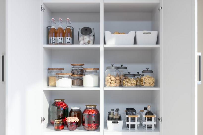 organized kitchen pantry with food items in a variety of glass containers and storage bins