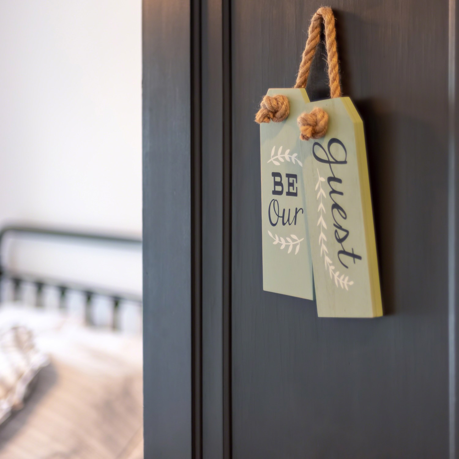 be a good home host with view into guest bedroom from an open door with a sign that says be our guest