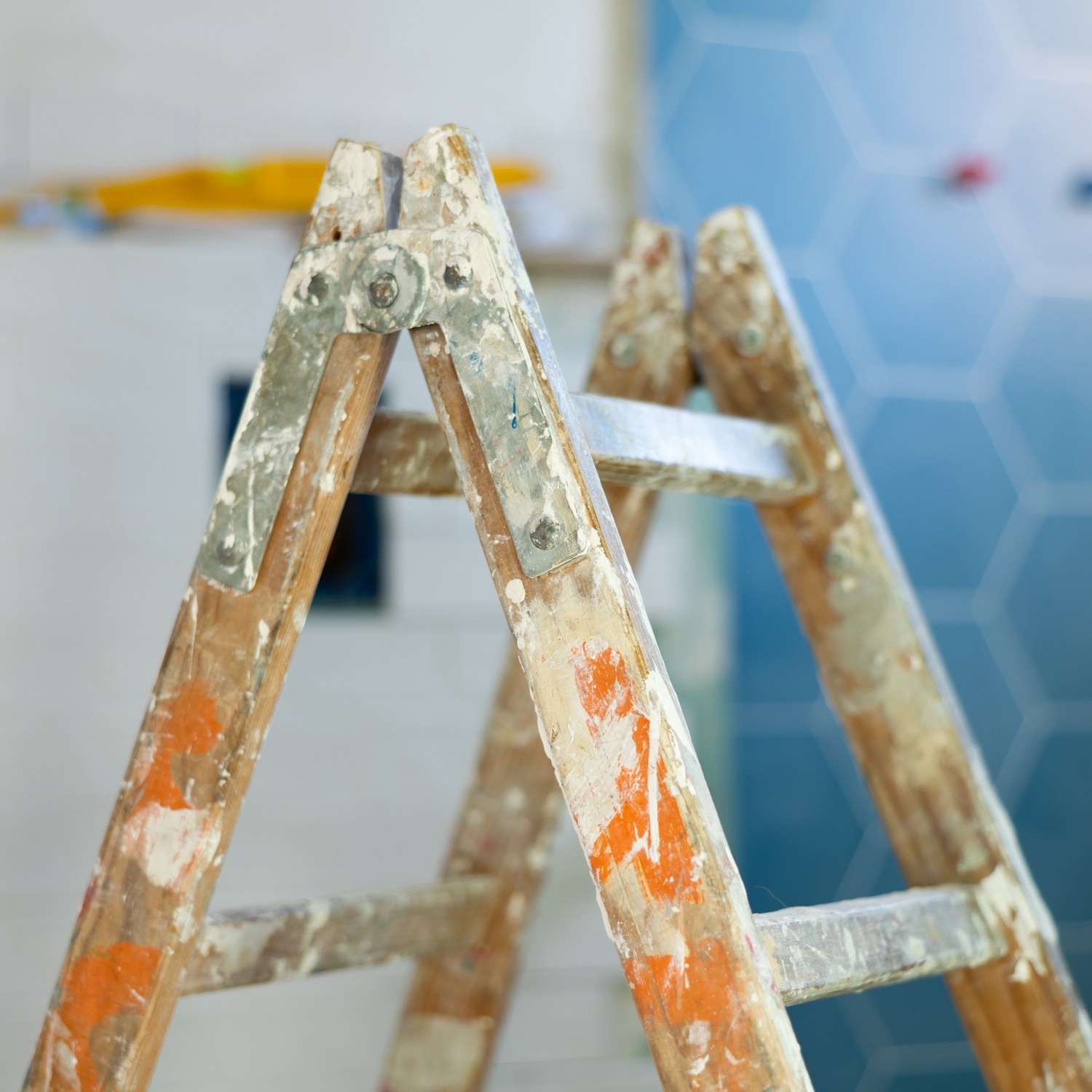 a wood ladder with paint splatter during easy and affordable home remodel ROI blurred blue tile in background