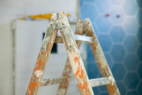 a wood ladder with paint splatter during easy and affordable home remodel ROI blurred blue tile in background