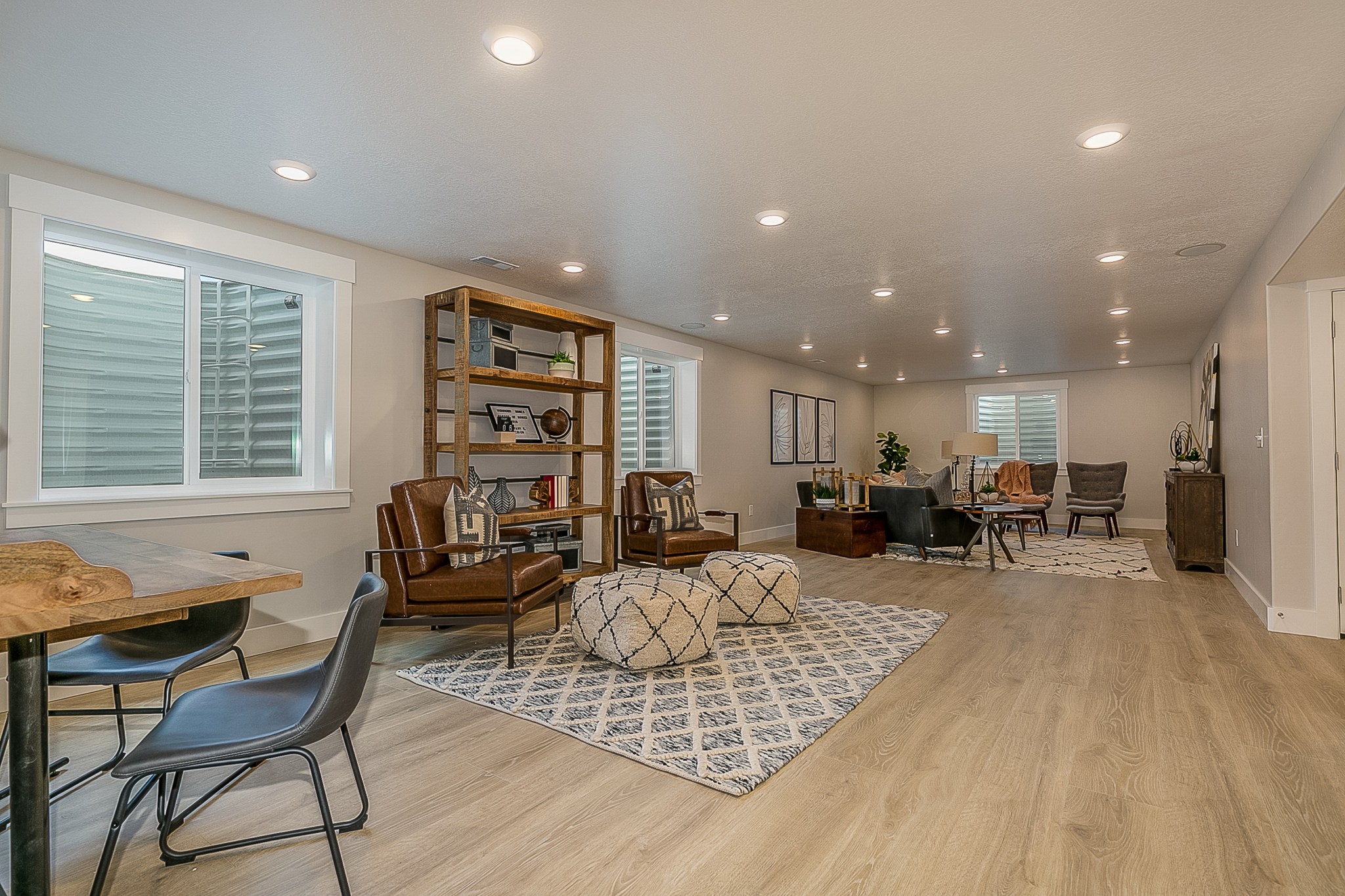 laminate wood flooring in a bright basement living area with lots of seating and egress windows
