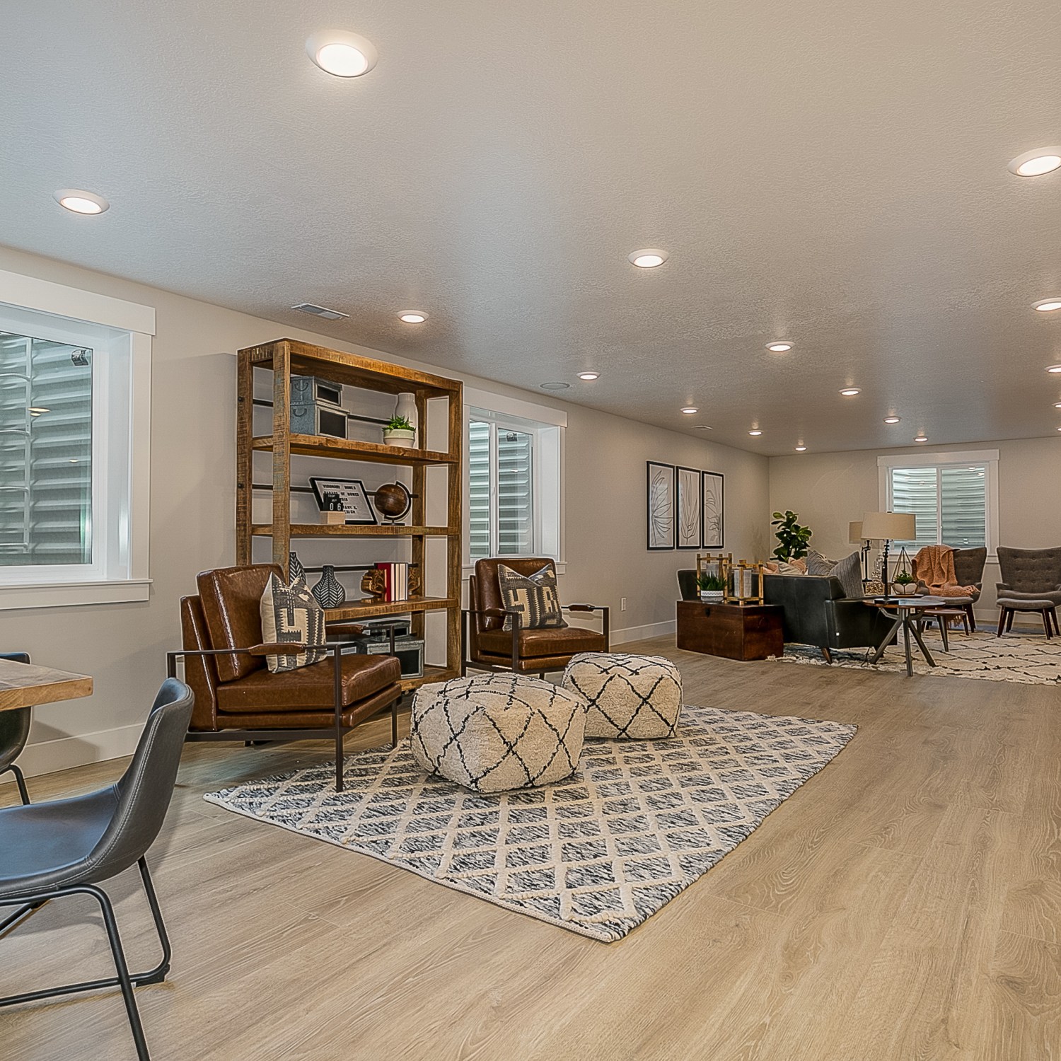 laminate wood flooring in a bright basement living area with lots of seating and egress windows
