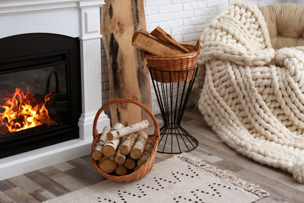 natural light in cozy living room brighter in winter with wicker baskets with firewood and burning fireplace