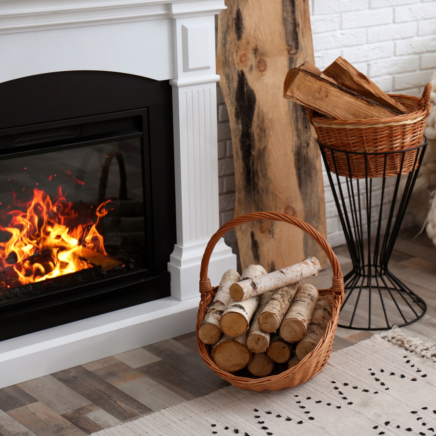 Natural light in cozy living room with wicker baskets with firewood and burning fireplace.