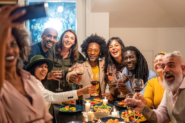 group of friends taking a selfie at dinner party toasting the celebration with holiday vibes