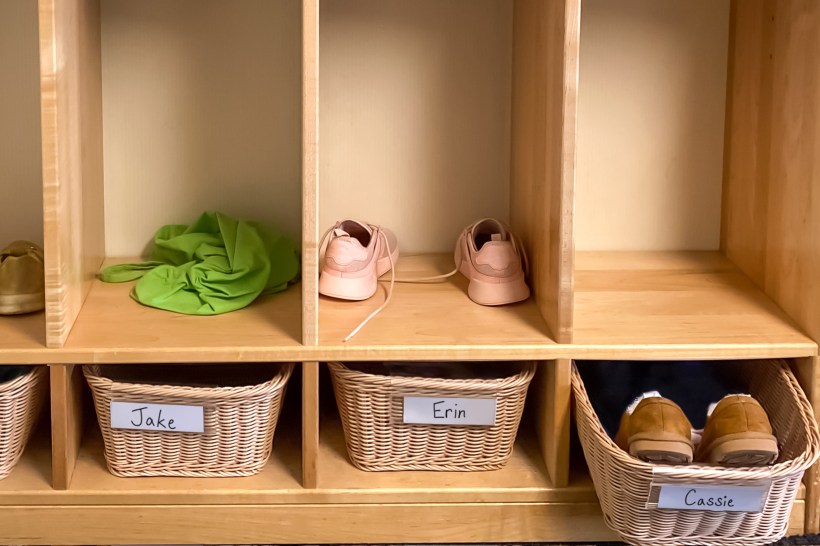 wicker baskets with names of family members as storage cubbies for shoes in entryway of a home