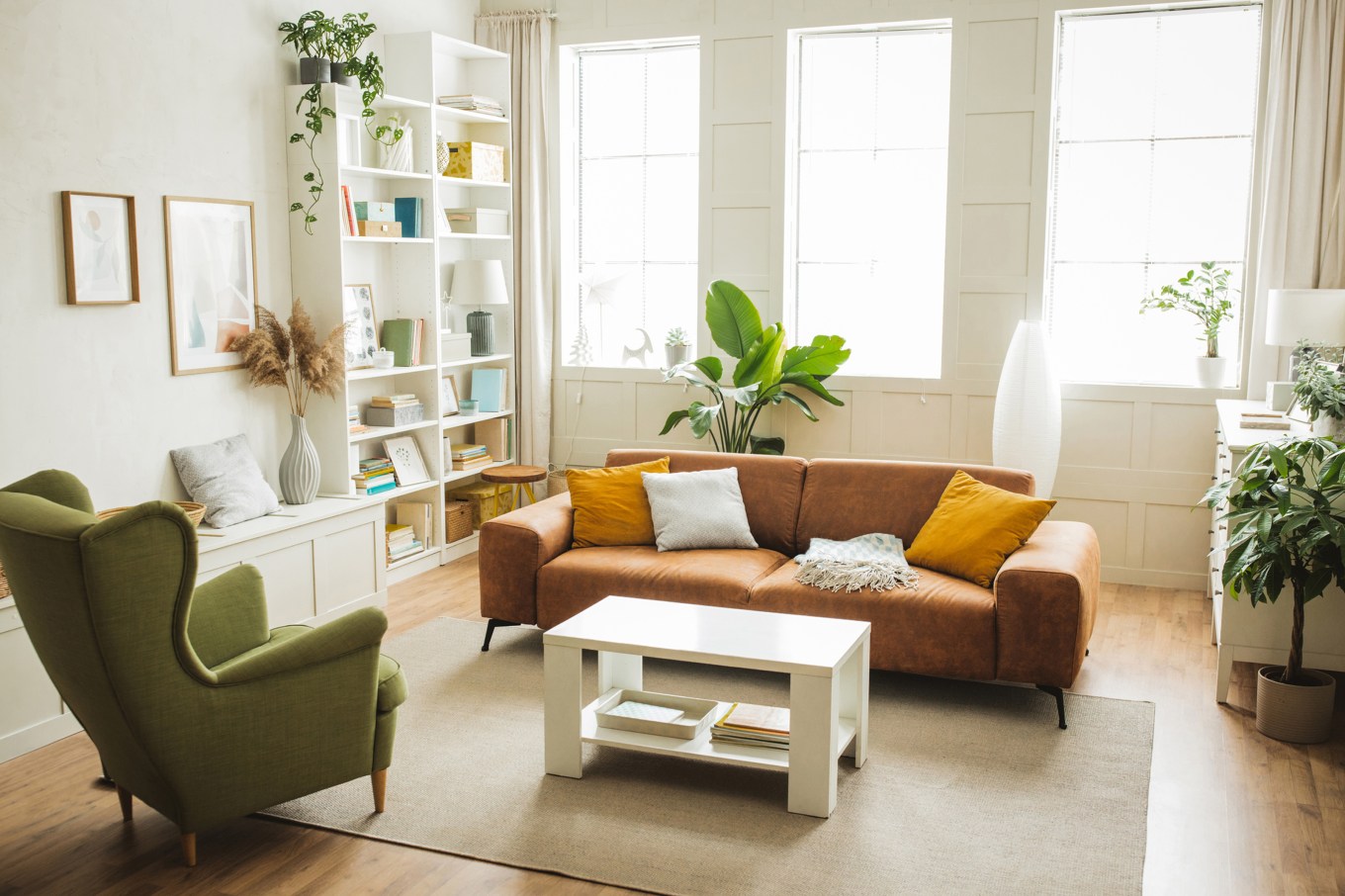 house interior of organized home living room with leather sofa, green armchair, storage, table and plants