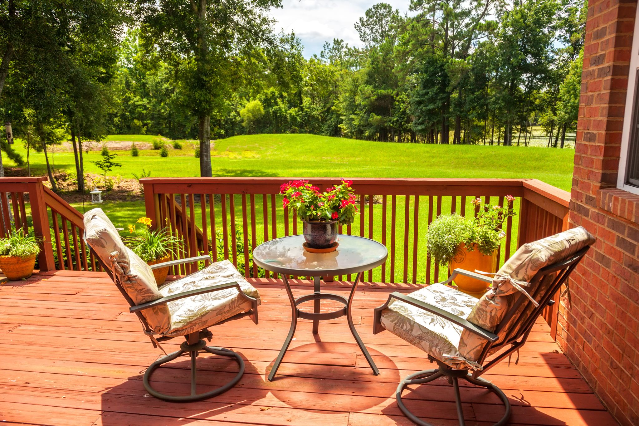 new deck overlooking back yard outside home in summer with patio chairs and table with flower pot