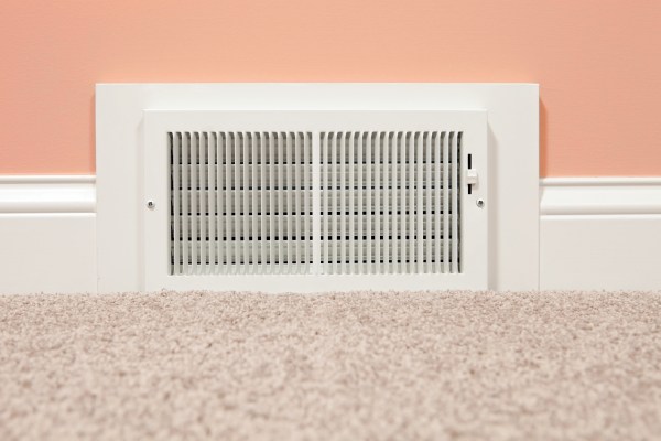 Air register vent, part of an HVAC system, in a wall close to the floor.