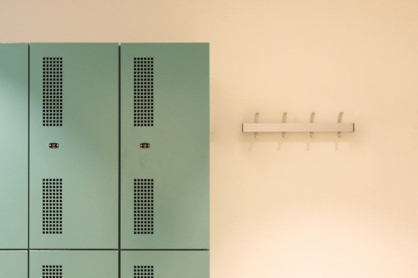 Turquoise lockers next to a coat rack.