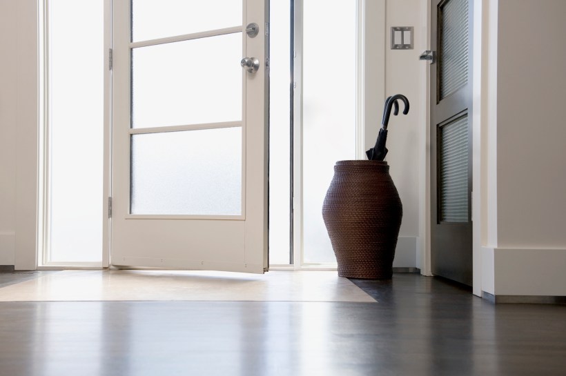 A woven basket umbrella stand next to a front door.