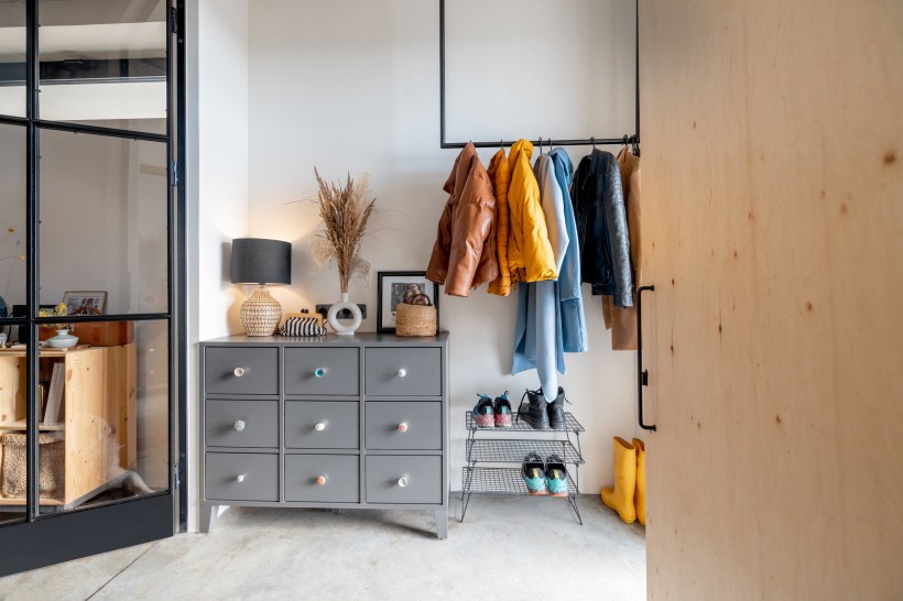 Foyer with a coat rack and dresser for storage.