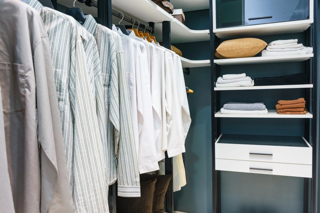 A neatly organized walk-in closet with clothes hanging on a rail and clothes folded on shelves.