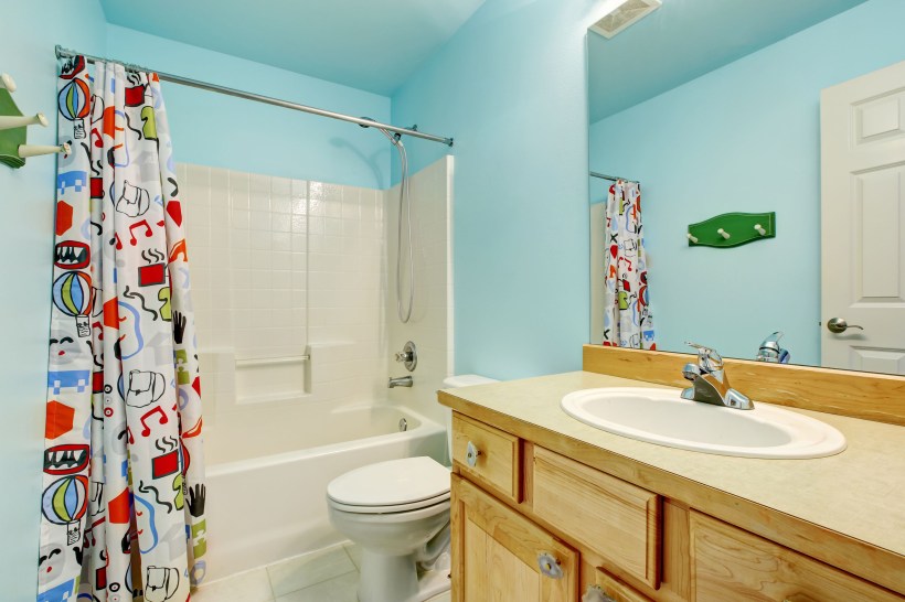 Built-in bathtub with colorful liner, blue walls, and wooden cabinets.