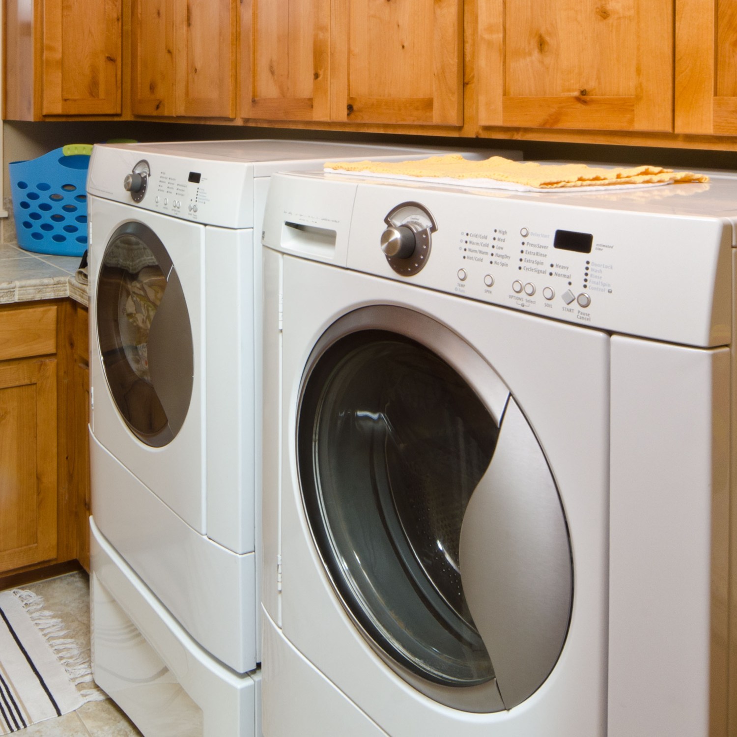 A modern laundry room with front loading washer and dryer and beautiful wood cabinets.