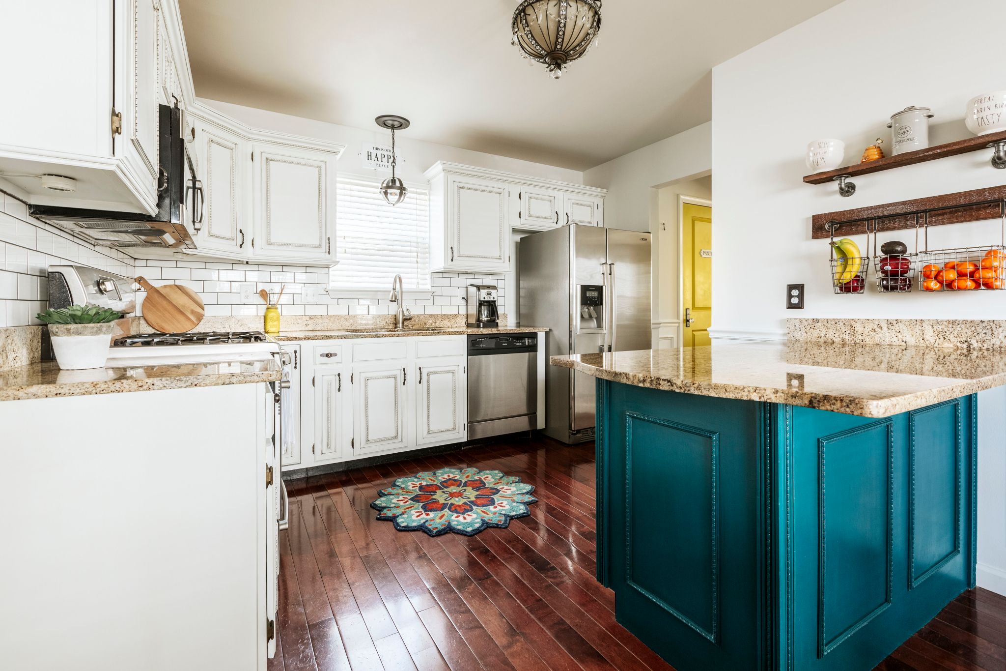 White kitchen with a pop of color on the pantry door and island counter.