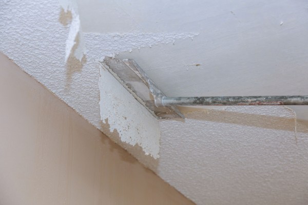 Image of a white popcorn ceiling being scraped away.