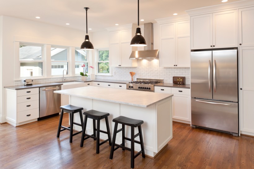 A beautiful white kitchen with stainless steel appliances.