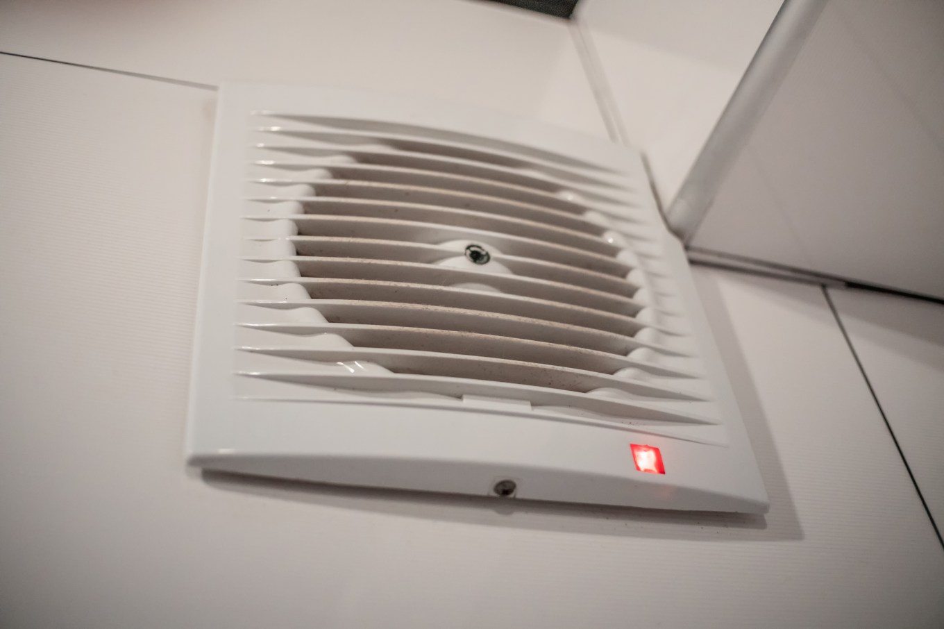 Close-up of a humidity-controlled fan with an indicator on the wall in the bathroom.