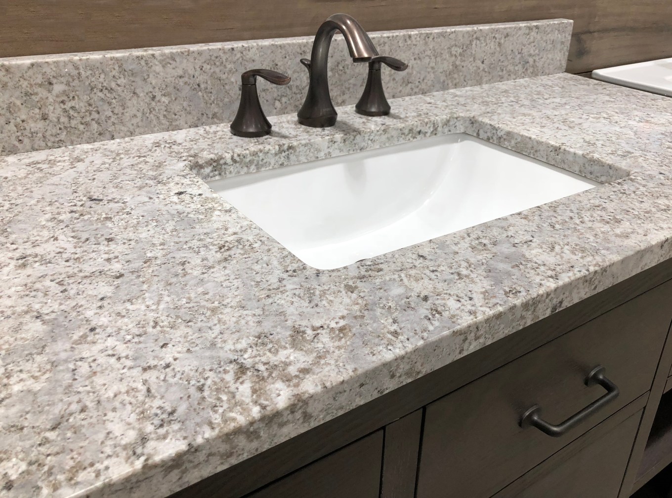 Granite bathroom counter over wooden vanity cabinet featuring a single sink.