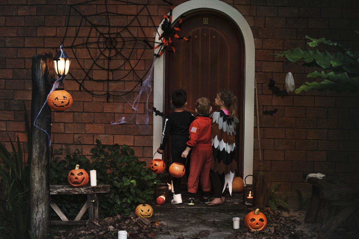 A group of young children at a door, trick or treating on Halloween