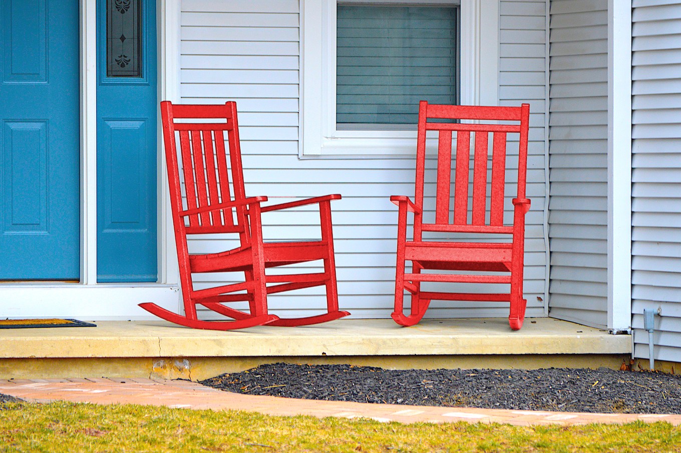 Vibrant, red rocking chairs sit on a porch adding a pop of color.
