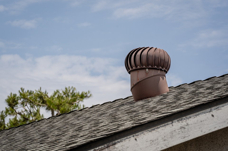 An older, residential house roof with an aluminum roof turbine vent.