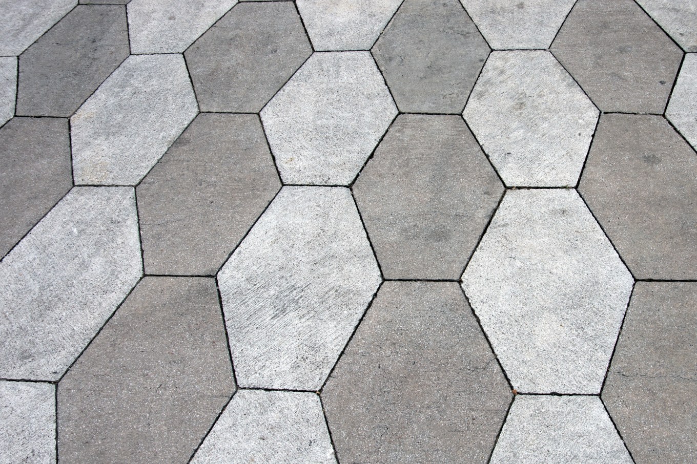 Gray, stained, hexagon-shaped concrete paving stones.