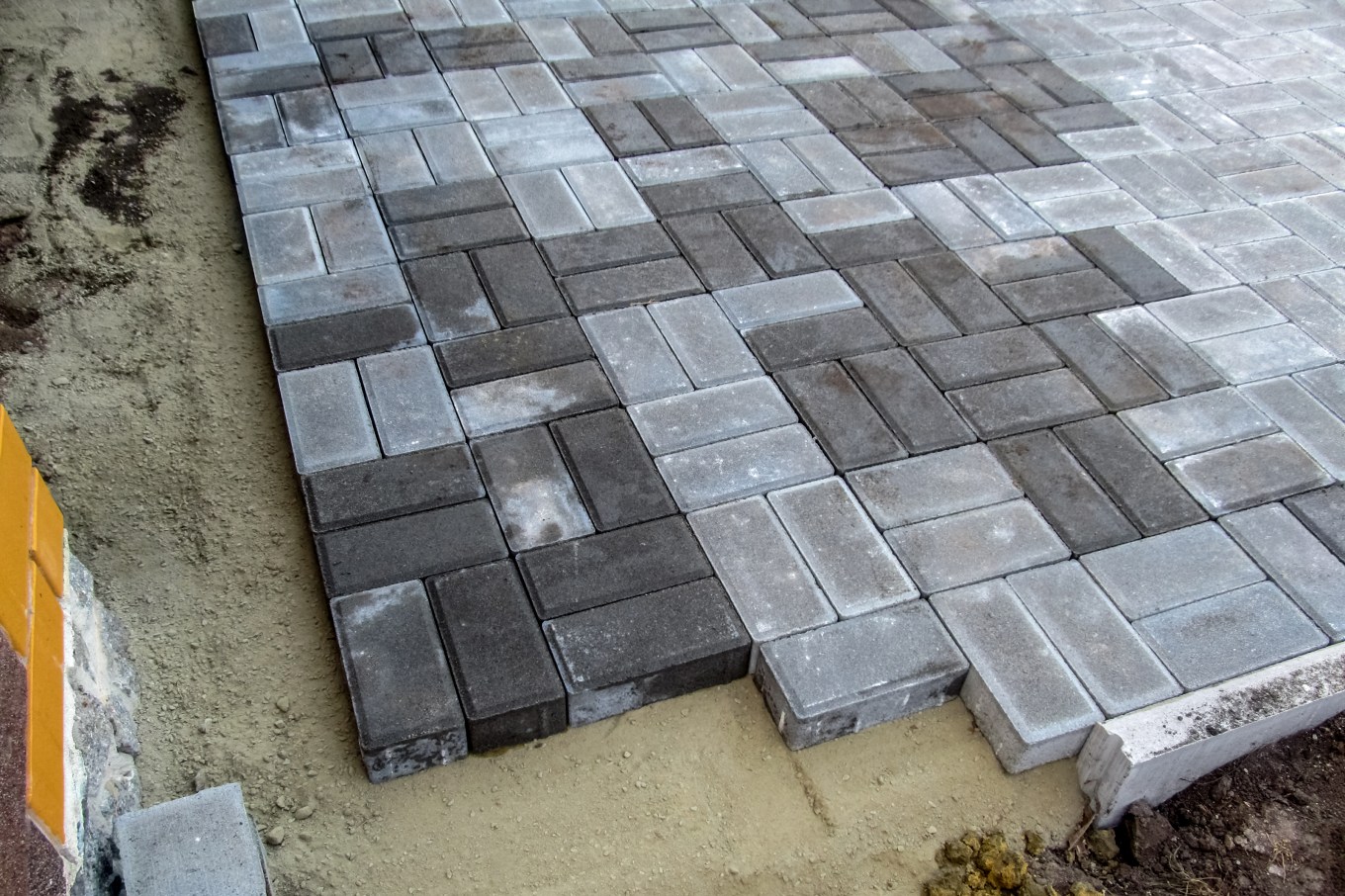 Brick paving slabs form a concrete patio with alternating colors.