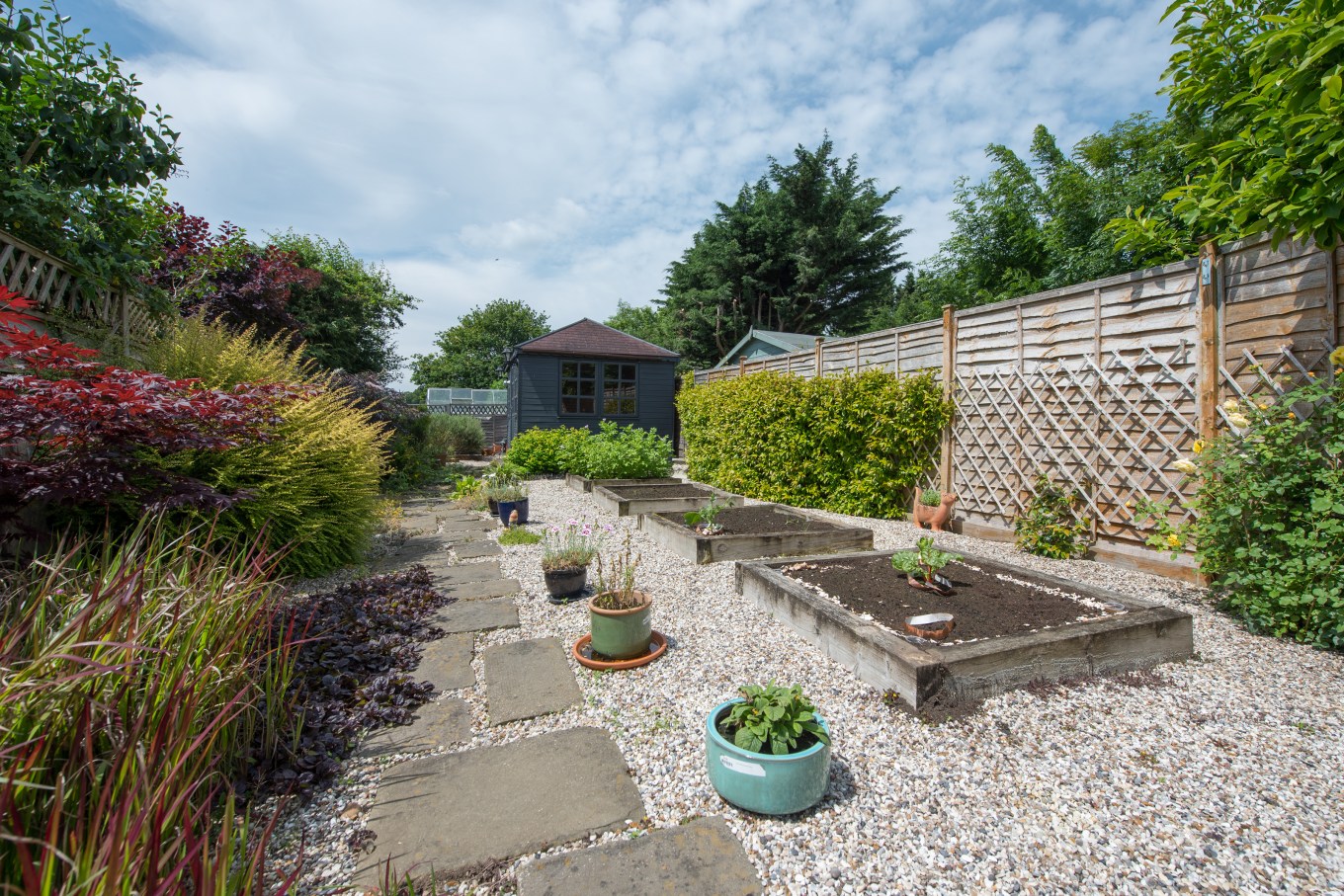 A backyard patio and garden with pavers outlined by gravel.