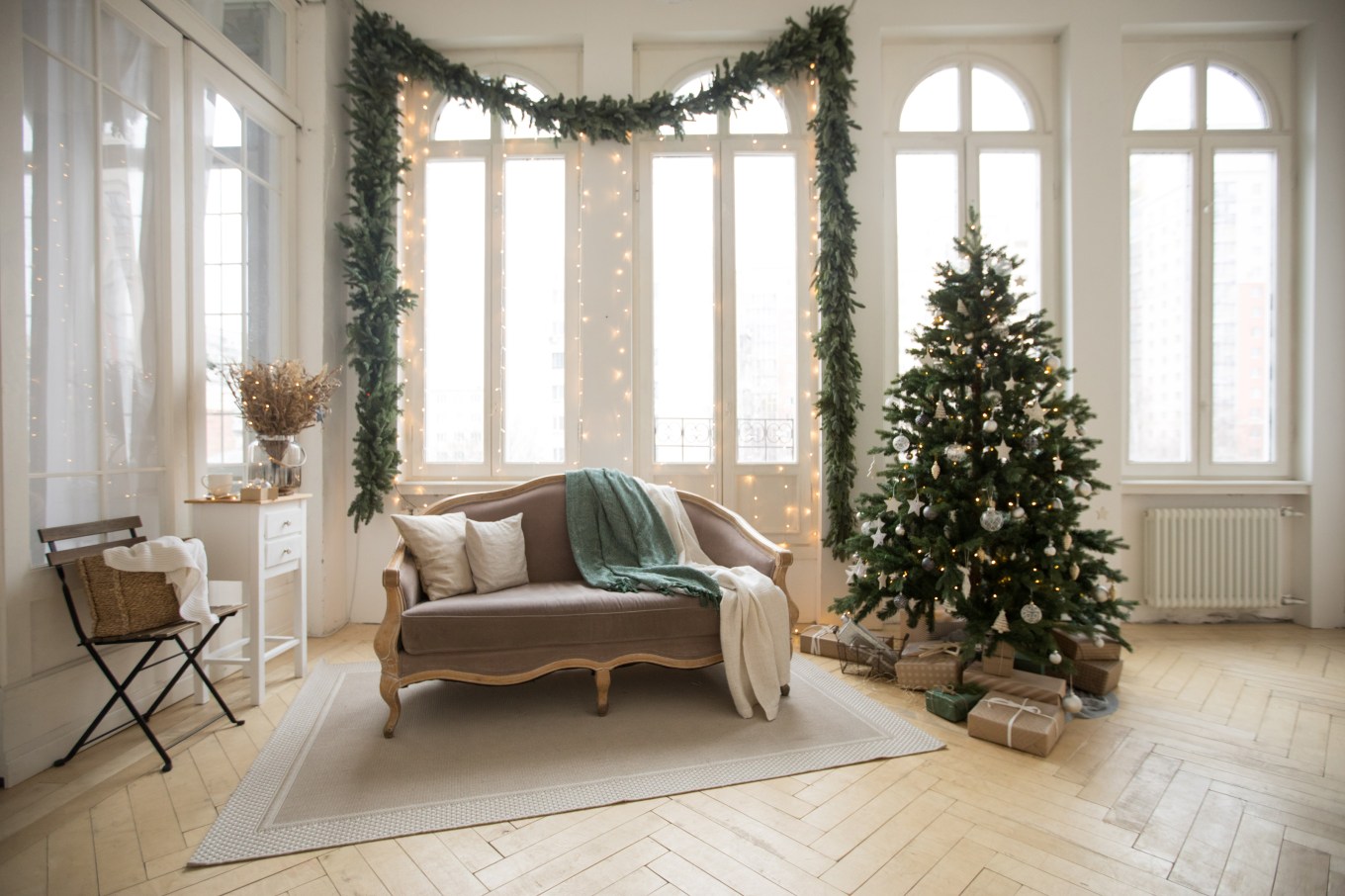 A pretty Christmas tree stands in a mostly undecorated living room, representing a simple, minimalist decorating style.