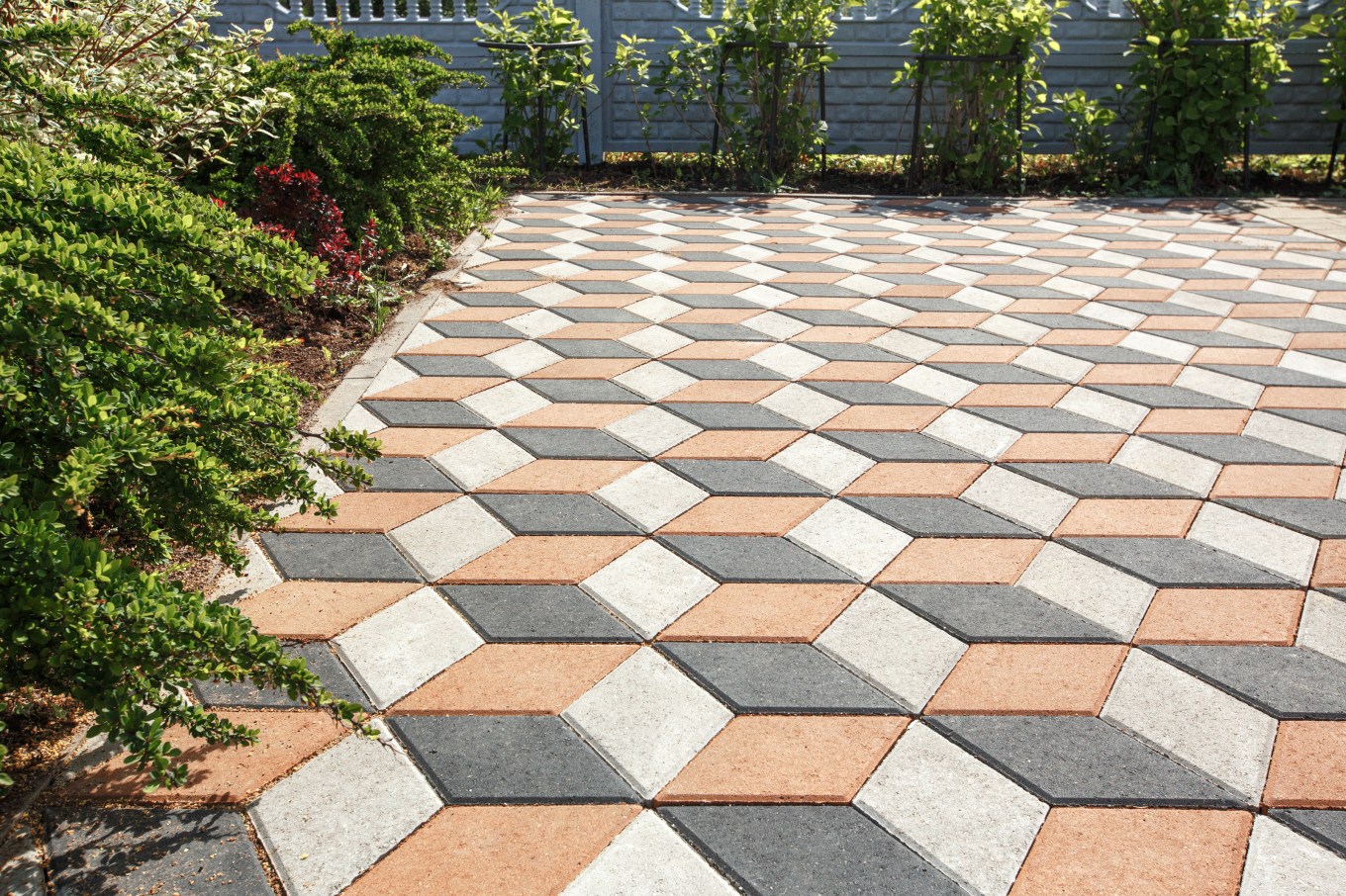 Concrete patio made of diamond-shaped paving tiles in alternating colors.