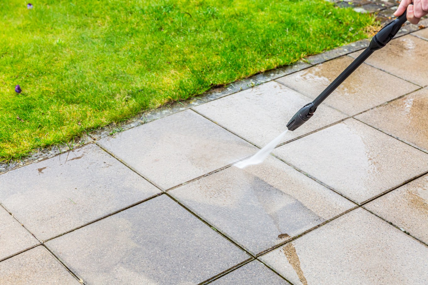 High-powered water cleaning of the resurfaced paving stones of a patio.