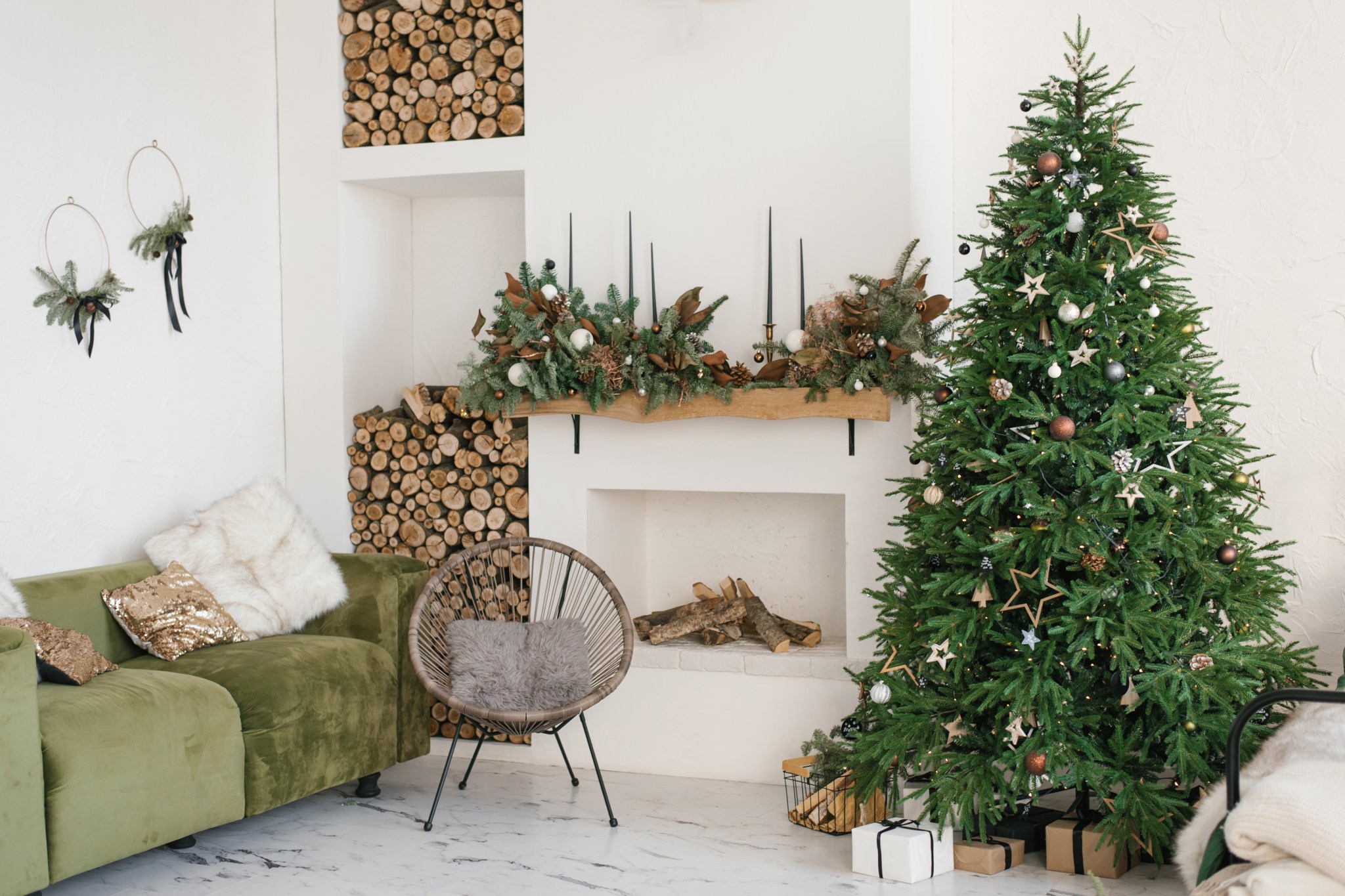 Rustic living room with a Christmas wreath, fireplace, firewood, sofa and Christmas tree, an example of Scandinavian decor.