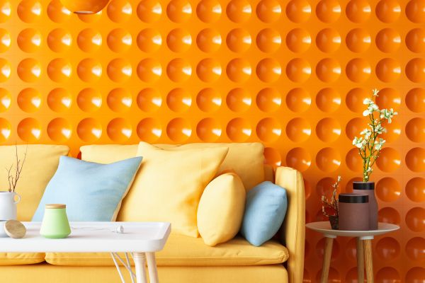 A colorful sofa with a vibrant orange wall is a good example of what's in when it comes to interior design for 2024.