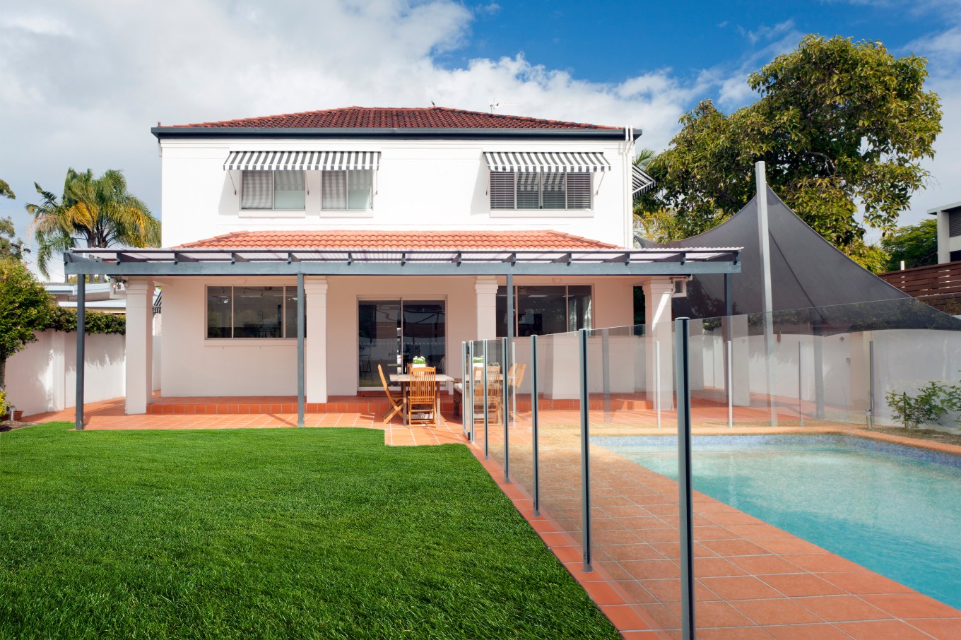 Modern backyard swimming pool with a glass pool fence.