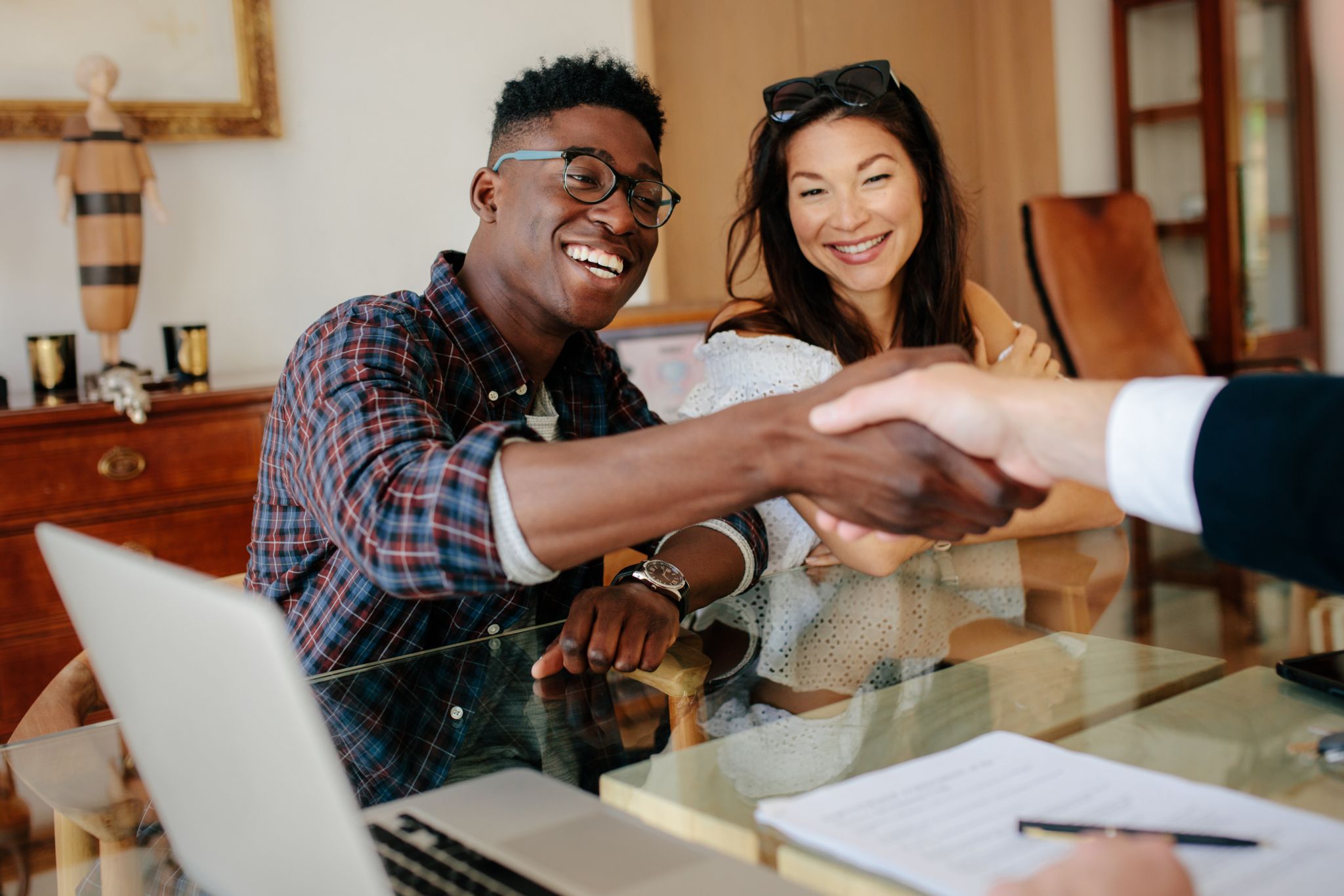 A happy couple shaking the hand of a Real Estate Agent after buying a house.