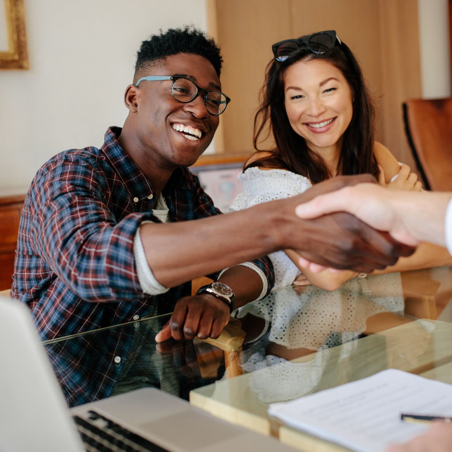 A happy couple shaking the hand of a Real Estate Agent after buying a house.